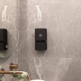 Black ONNYBODY body wash, shampoo and conditioner dispenser mounted on a marble bathroom wall