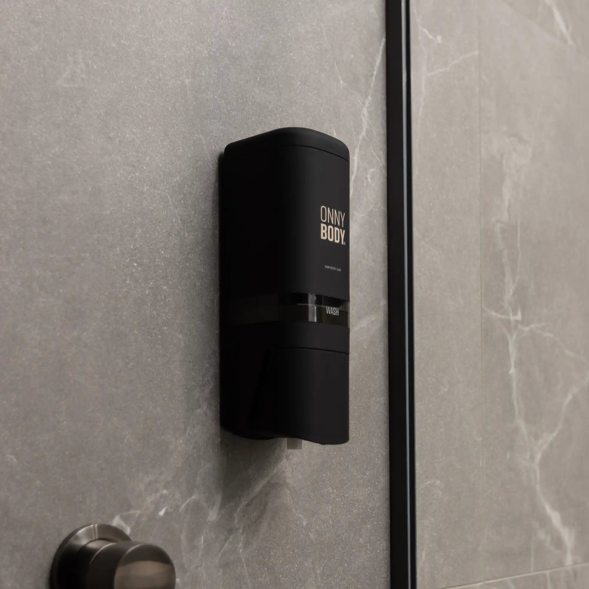 one black ONNYBODY dispenser attached to a tiled bathroom wall.