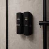 two black ONNYBODY dispensers attached to a tiled bathroom wall.