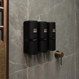 Three black ONNYBODY dispensers mounted on a grey tiled wall with a gold shower handle.